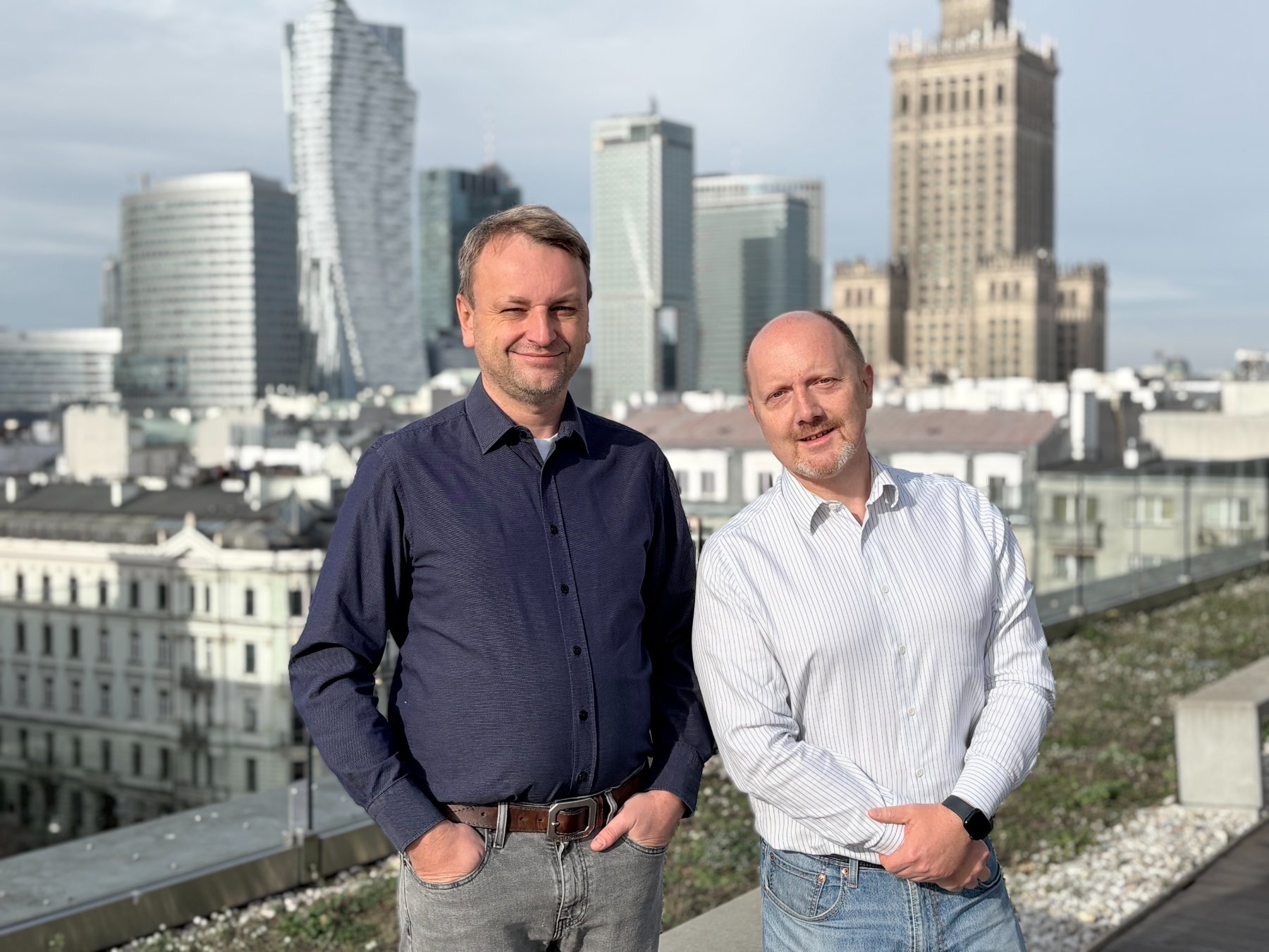 Marek Wrobel and Tomasz Polikowski on a rooftop with the Warsaw skyline