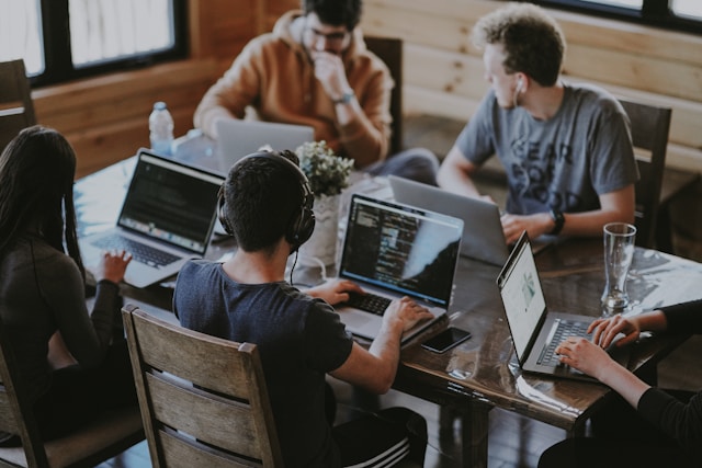 Team of developers collaborating together on laptops